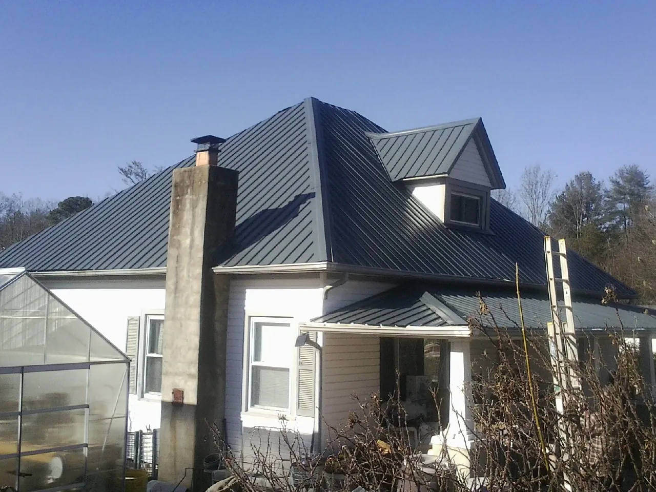 Dark blue standing seam metal roof on a white farmhouse with dormer — Slate & Tile Roof Repair by Roofing Brothers in Townley