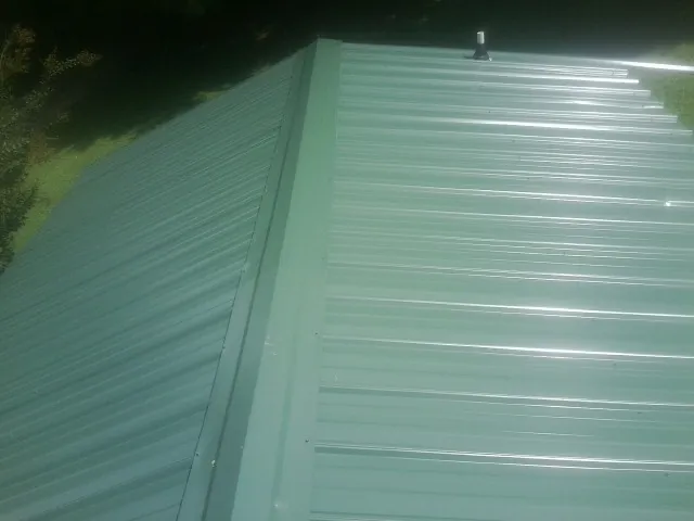 New green metal panels meeting at the ridge of a roof — Flat Roof Repair work by our crew in Townley