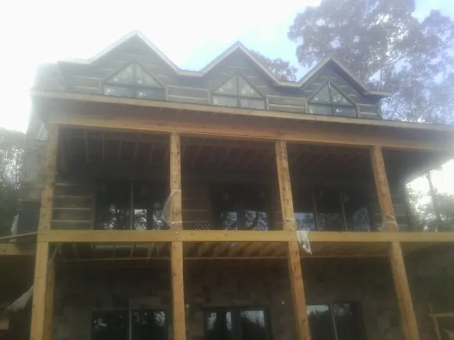 Dormers and porch framing on a large log home under construction — Roof Coating work by our crew in Townley