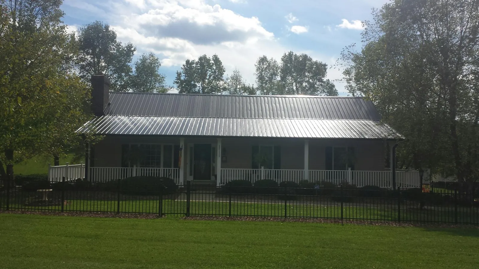 Gray metal roof on a brick ranch with a full width front porch — Gutter Guard Installation work by our crew in Townley