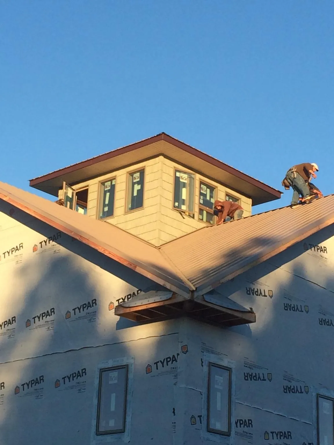 Roofers working around a rooftop cupola on a new metal roof at sunset — Roof Waterproofing in Townley by Roofing Brothers